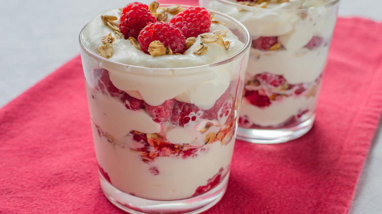 Traditional Scottish dessert with raspberry, whipped cream, roasted oatmeal and whisky on a table.