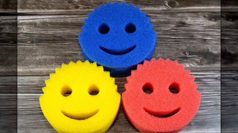 Blue, yellow, and red Scrub Daddy sponges on a wooden table