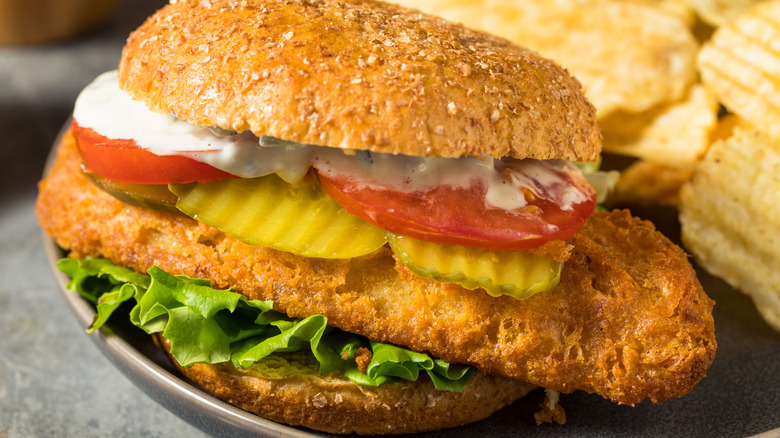 Fried fish sandwich with pickles, lettuce, and tomatoes