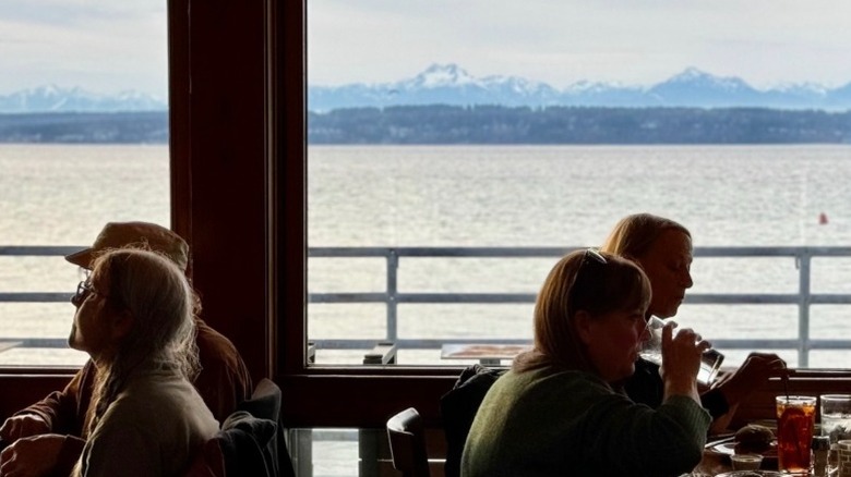 Diners at Ray's Boathouse restaurant in Seattle with mountains and the Puget Sound seen out the windows behind them.