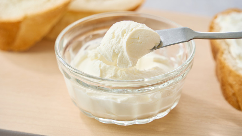 Cream cheese being scooped out of a dish.