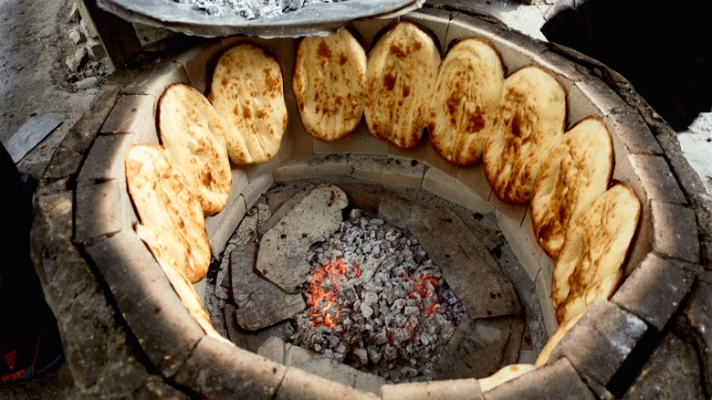 Naan bread cooking in a tandoor oven