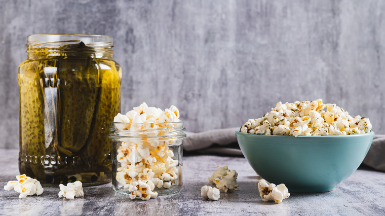 Bowl of popcorn next to jar of pickles