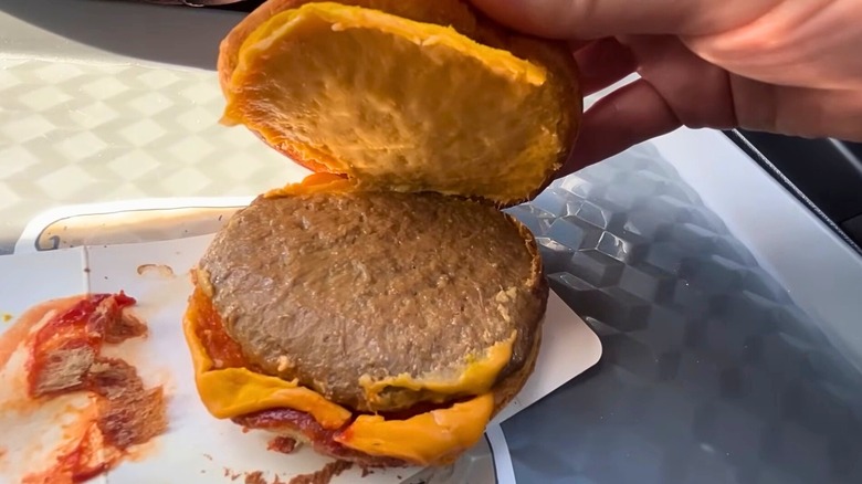 An upsetting cheeseburger from 7-Eleven sitting on a plate