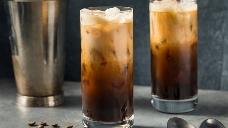 Two glasses of iced shaken espressos with milk in tall glasses