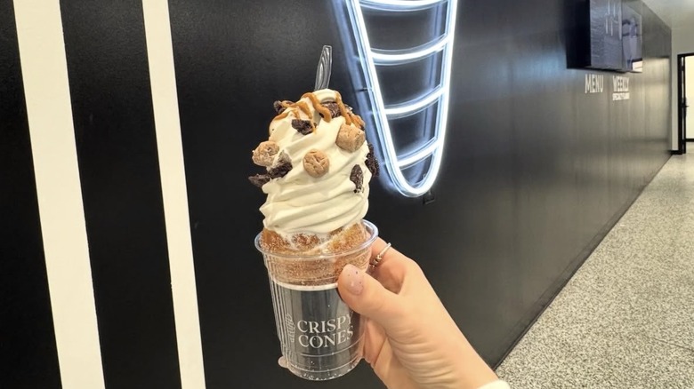 A hand holding a Crispy Cone in a cup, with vanilla ice cream and toppings