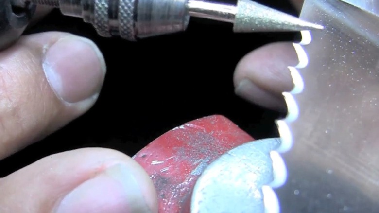 Closeup of a conical Dremel bit used on a serrated knife blade.