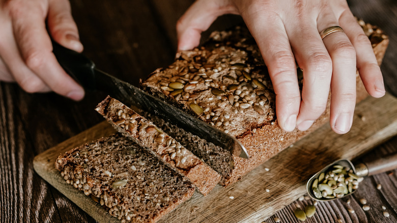 Person cutting bread with a serrated knife.