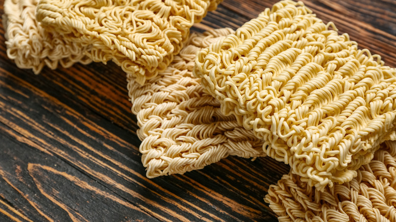 Blocks of dry instant noodles on a wooden surface.