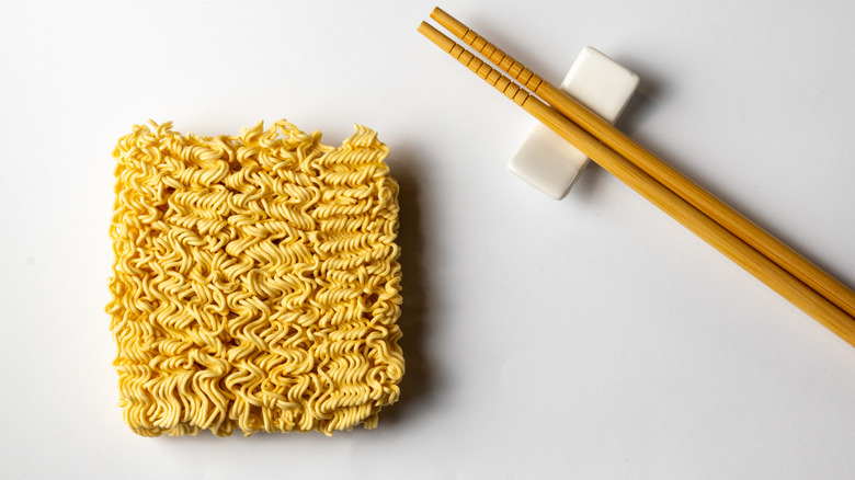 Block of dry instant ramen noodles and chopsticks.