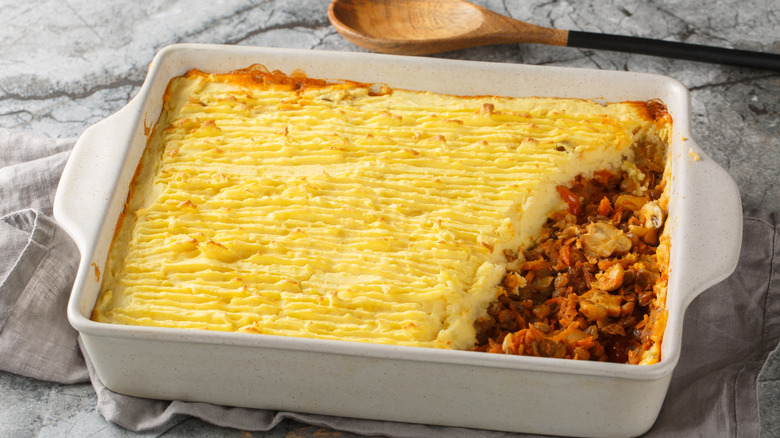 Shepherd's pie with a serving scooped out, revealing the filling underneath, in a white baking dish