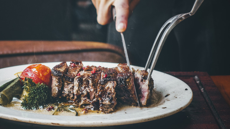 A man cutting into his steak dinner