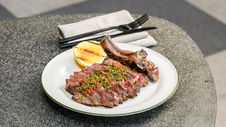 Ribeye on white plate with chimichurri drizzled on