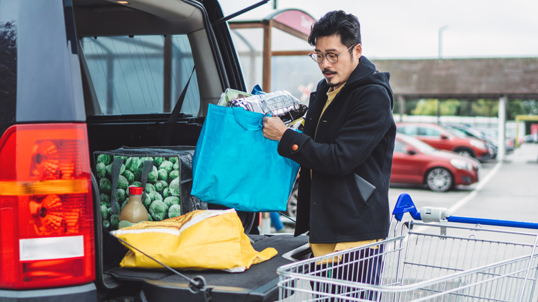 A man loading reusable shopping bags after a shopping trip