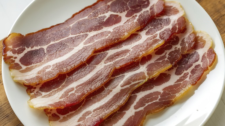 Raw bacon on white plate