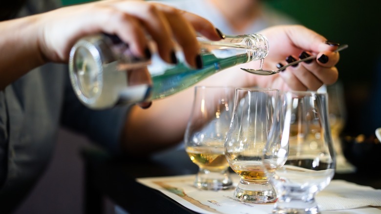 A bartender adding water to a whiskey glass