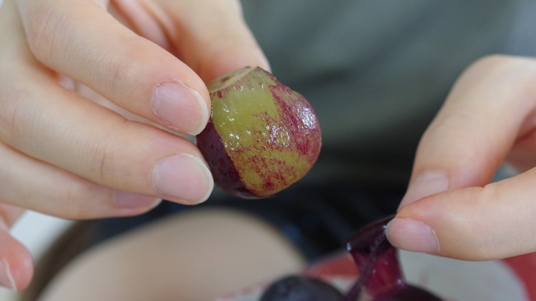 Hands peeling grapes