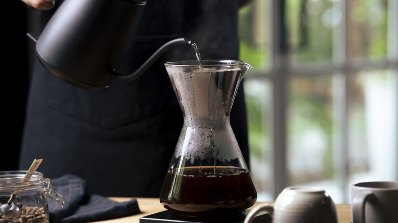 Person making pour-over coffee adding water to coffee filter