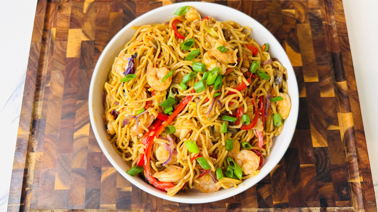 Shrimp lo mein topped with scallions in bowl