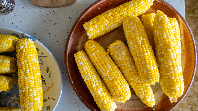 Several ears of cooked corn on serving platters