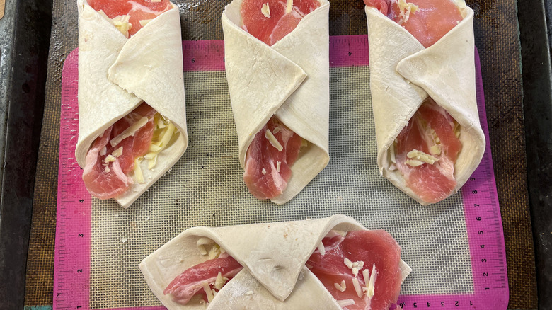 Savory, uncooked pastries on a silicone baking sheet.