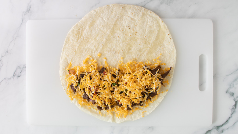 flour tortilla partially covered with shredded cheese