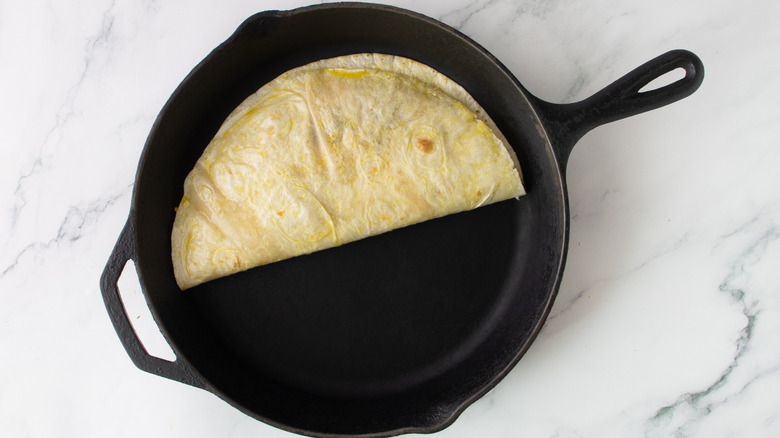 folded flour tortilla in a black cast-iron frying pan