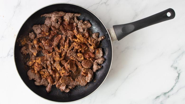 cooked steak strips in a black frying pan