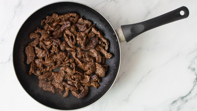 cooked steak strips in a black frying pan
