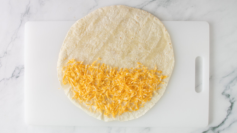 flour tortilla partially covered with shredded cheese