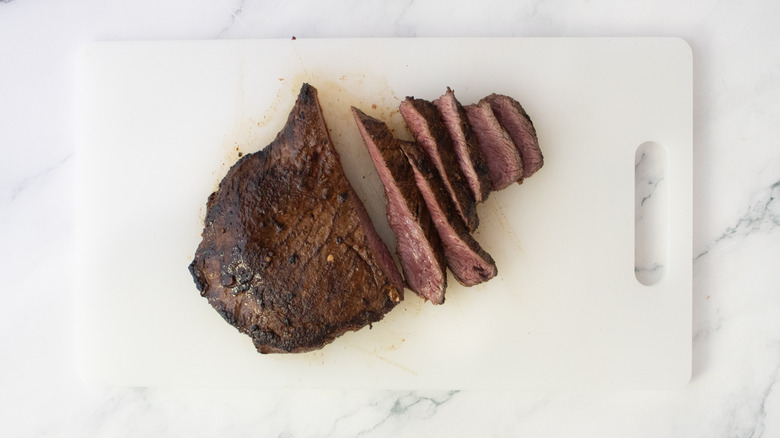 Sliced seared skirt steak on a white cutting board