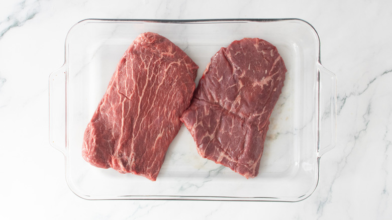 Two skirt steaks in a glass casserole dish