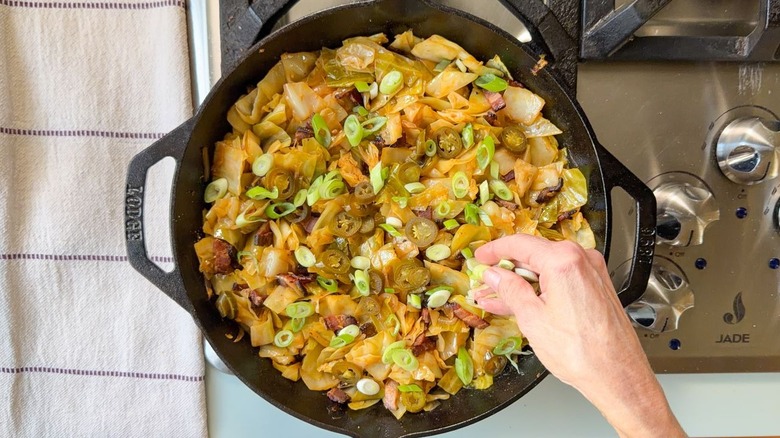 Adding pickled jalapeños and sliced scallions to skillet cowboy cabbage
