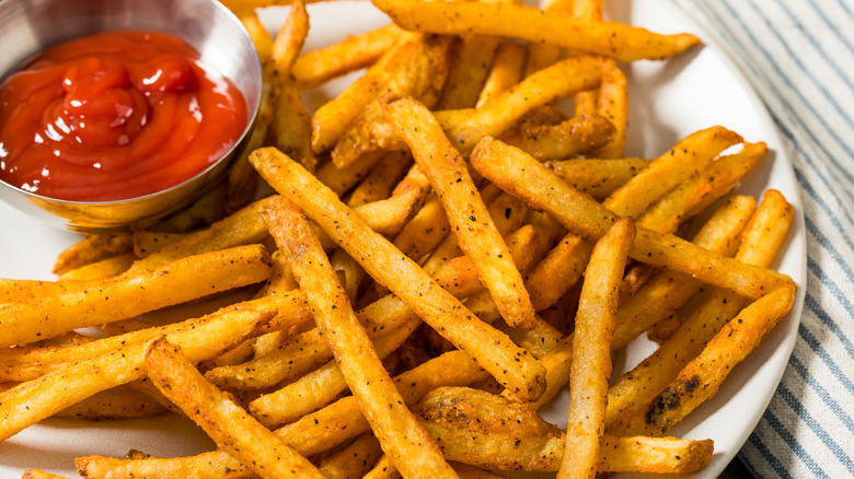 french fries on a plate served with ketchup