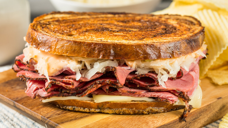 Homemade Russian Reuben sandwich with with chips behind it.