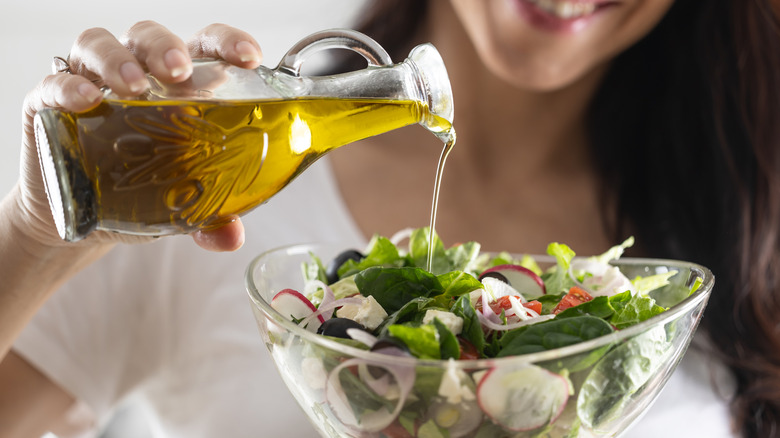 Person pouring dressing onto a bowl of salad