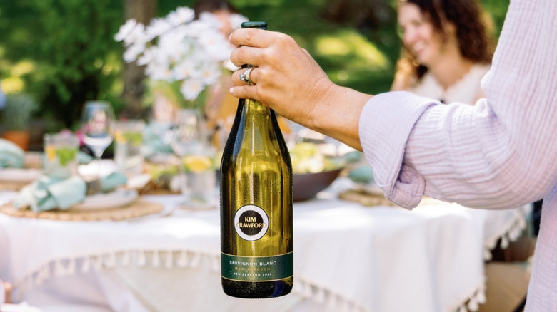 A person holding a bottle of Kim Crawford Sauvignon Blanc