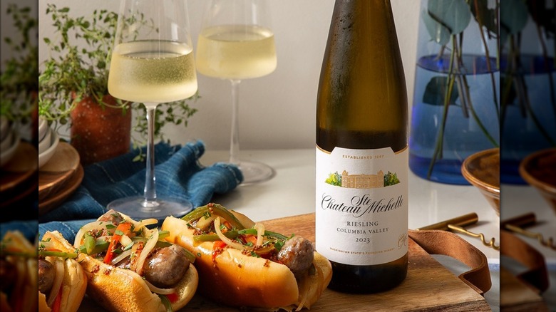 A bottle of Chateau Ste. Michelle Riesling on a wooden board with hot dogs