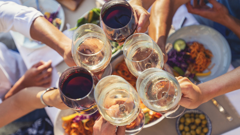 People clinking wine glasses at a backyard party