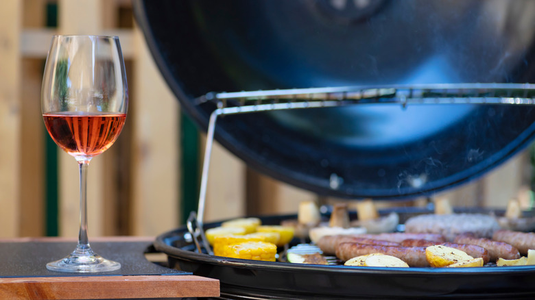 A glass of wine next to a grill