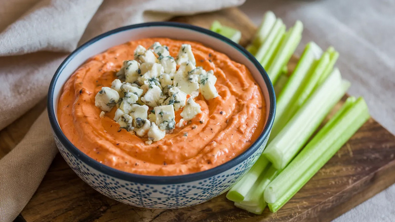 A bowl of creamy Buffalo chicken dip topped with blue cheese.