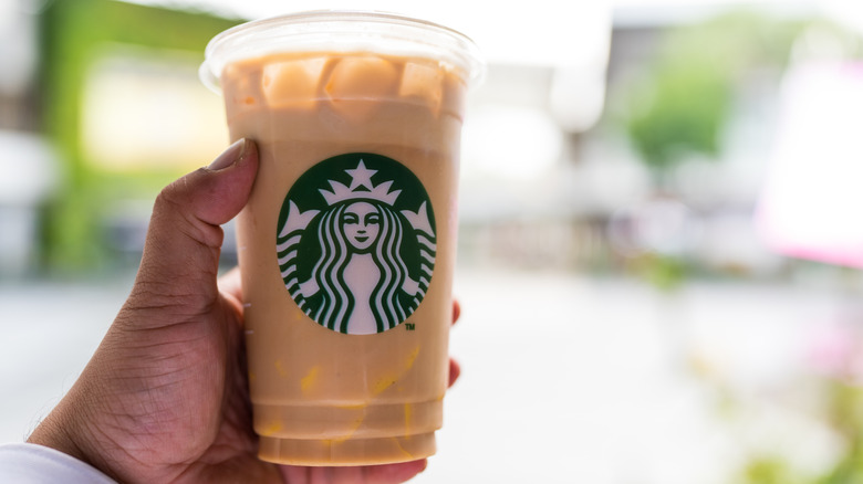 A hand holding an iced Starbucks latte