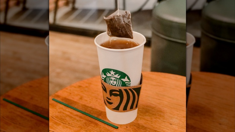 A tea bag being dunked into a Starbucks cup