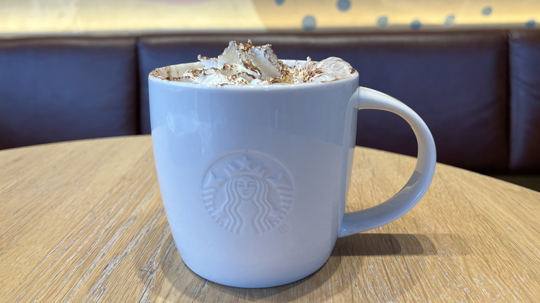 A white ceramic mug of Starbucks hot chocolate on a wooden coffee table