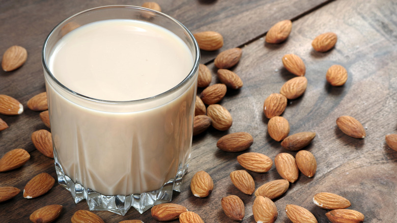Glass of almond milk surrounded by almonds