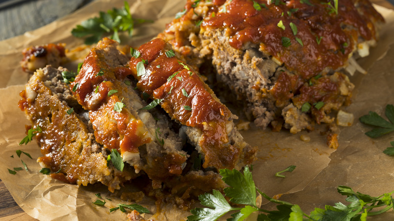 Meatloaf with ketchup and herbs on parchment paper.