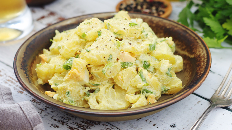 A bowl of potato salad on a wooden table.