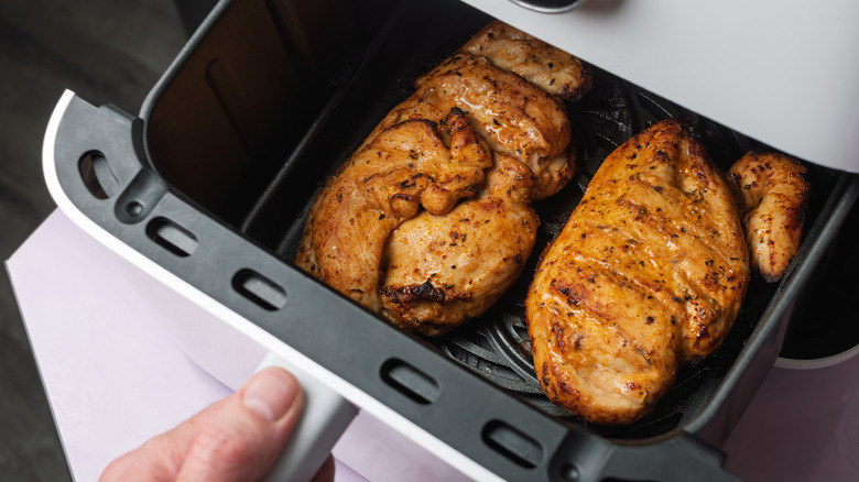 Cooked chicken inside an air fryer basket.