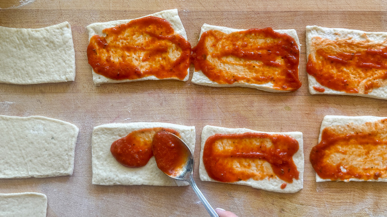 Pizza dough rectangles with sauce on them