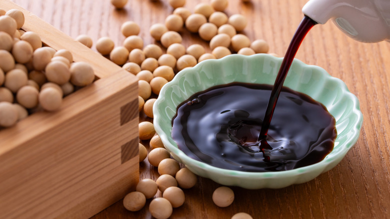 Soy sauce is poured into a small, green dish.